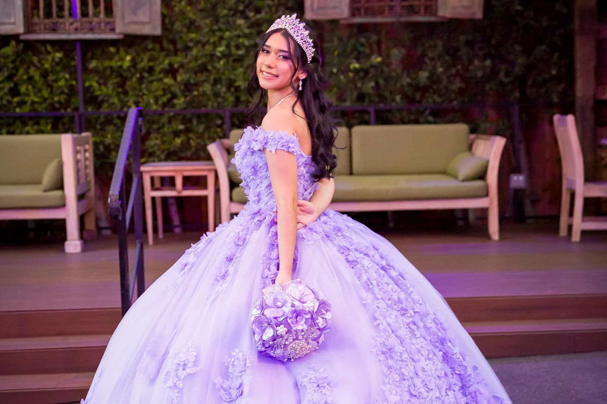 Quinceañera in a lavender ball gown and tiara holding a floral bouquet