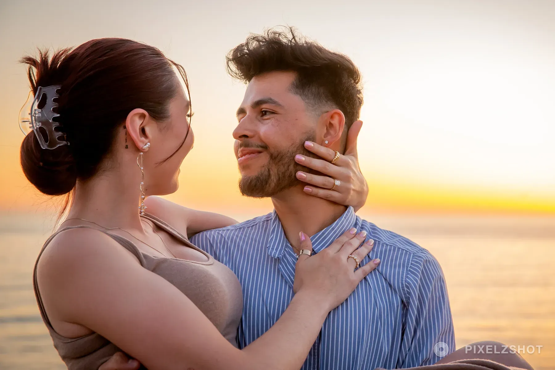 Danielle and Mathew looking at each other at golden hour, one hand resting along the other's jaw