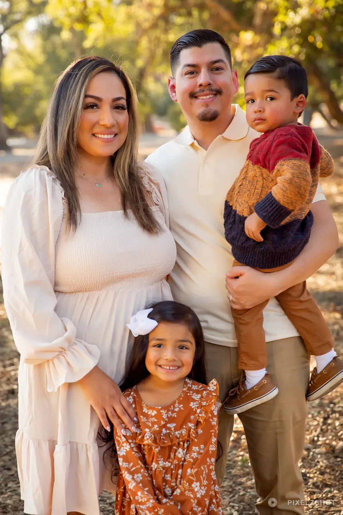 The family of four grouped together under the oaks, the youngest up on his father's arm and his sister in front