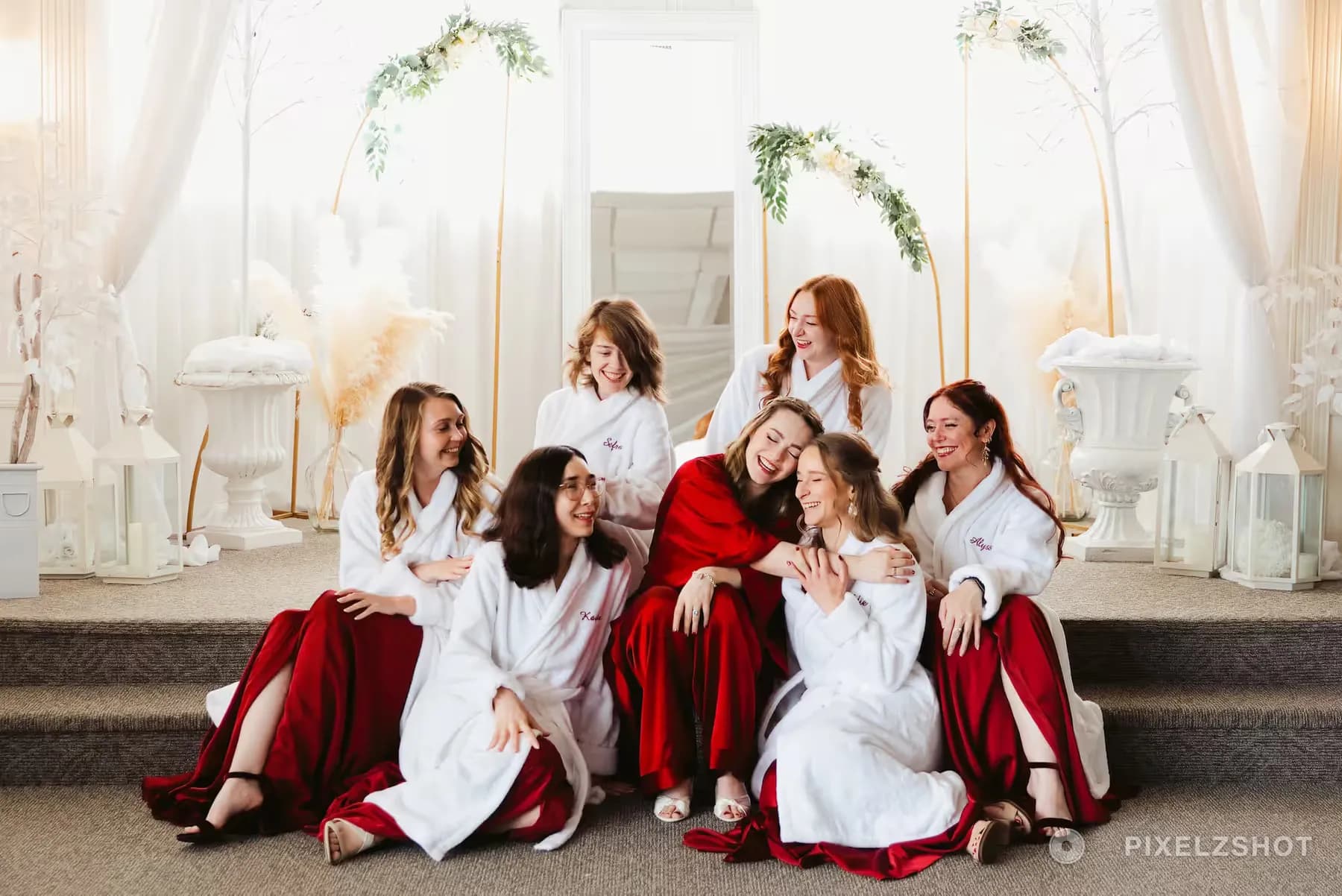 The bridal party laughing and leaning on each other on the steps of the getting-ready suite