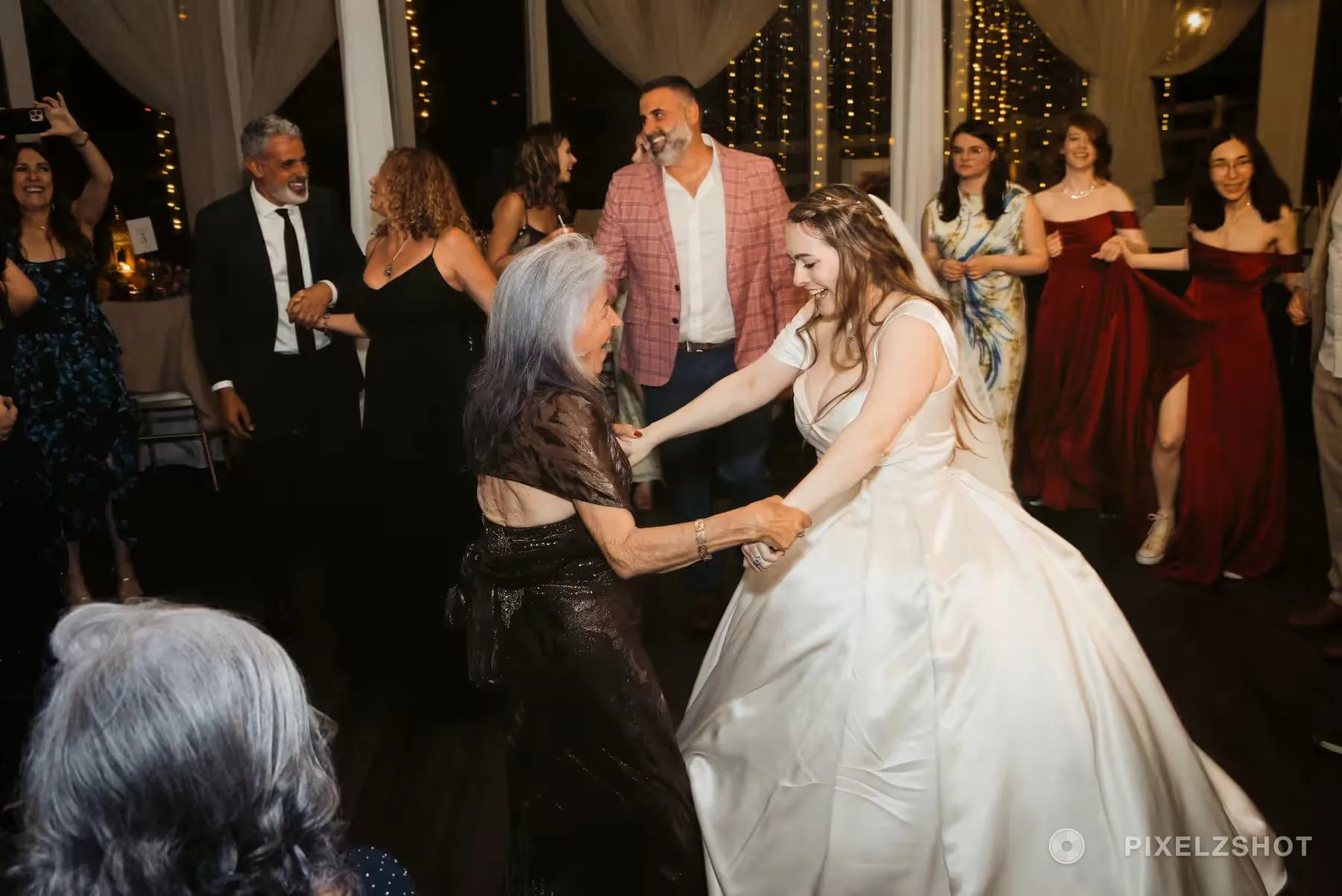 The bride dancing with a guest on a full floor, both holding hands and laughing
