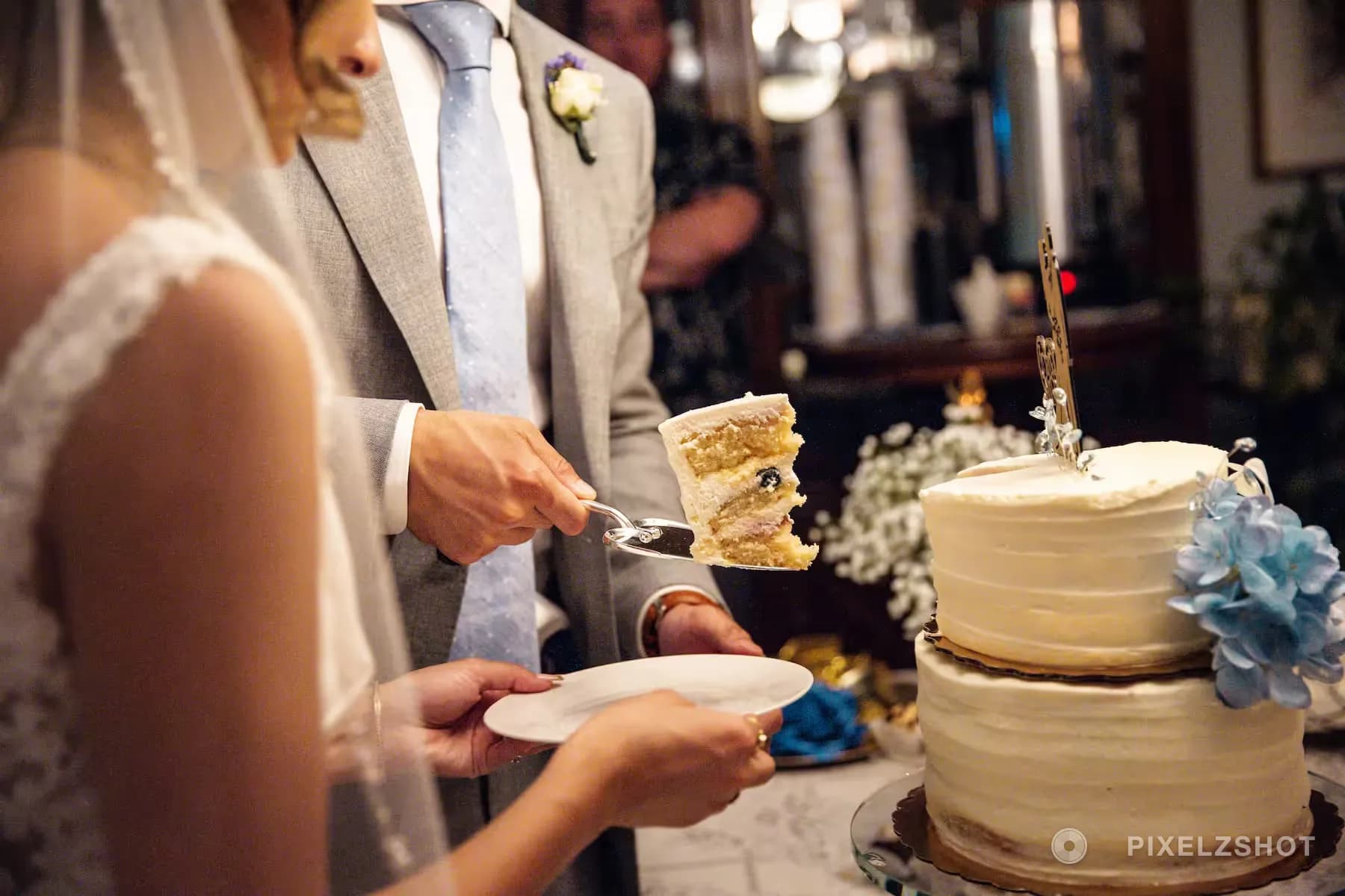 The first slice lifted off the cake server onto a white plate, the hydrangea-trimmed cake beside it