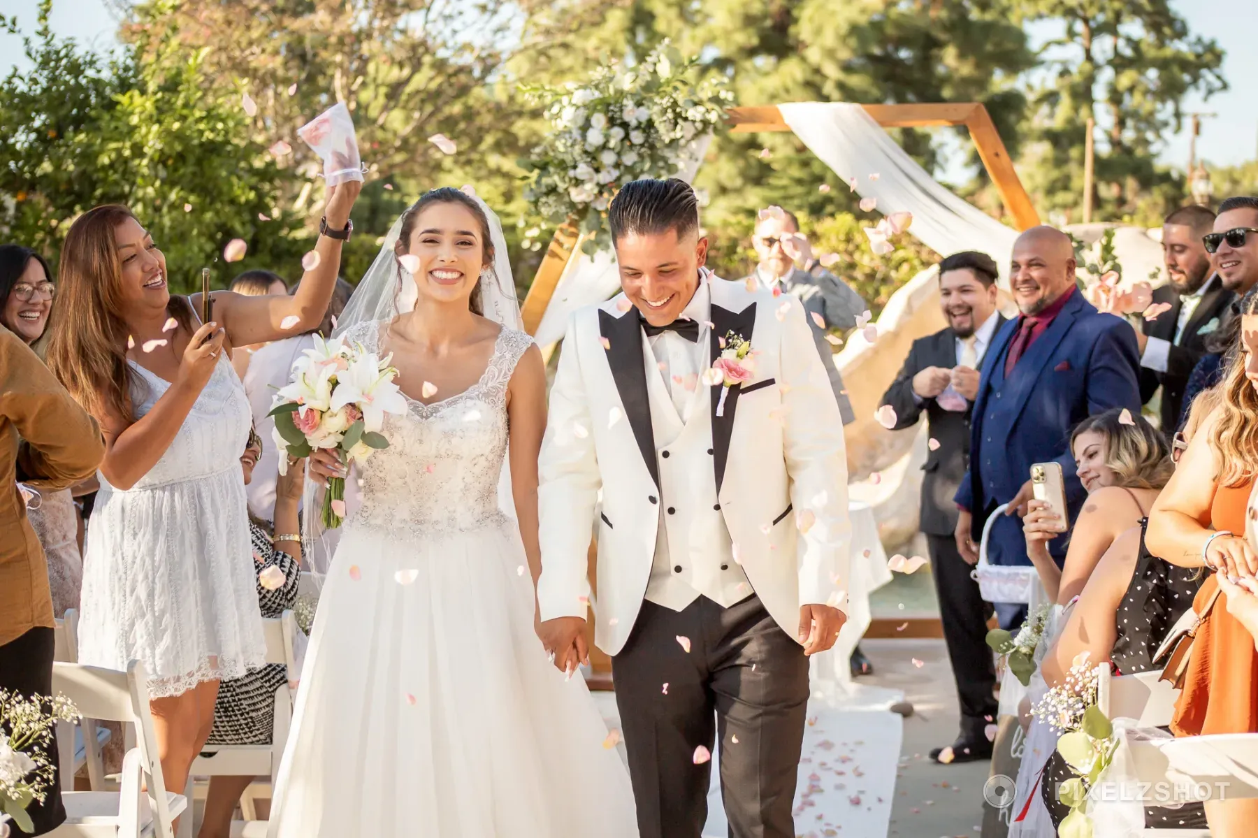 Leslie and Tito walking back down the aisle hand in hand as guests shower them with rose petals