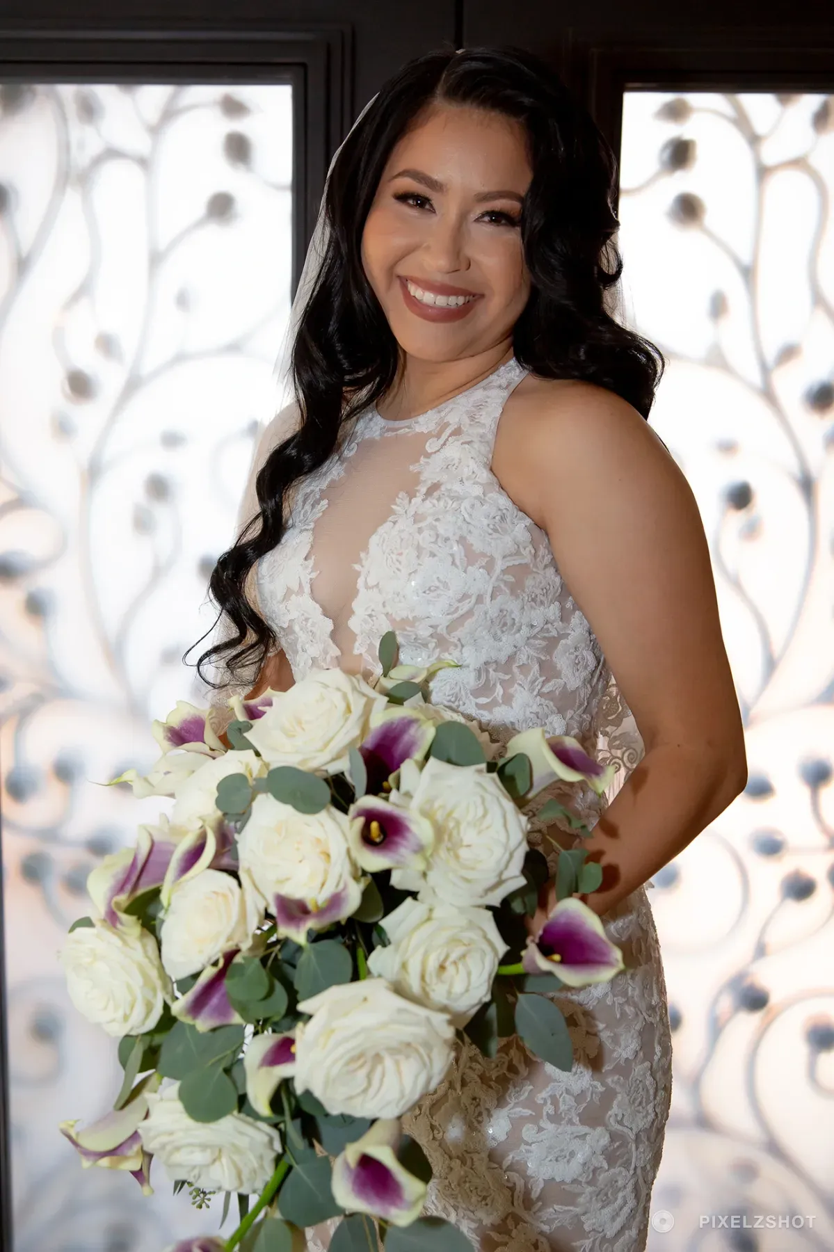 Natalie in a lace halter gown holding a cascading bouquet of white roses and plum calla lilies