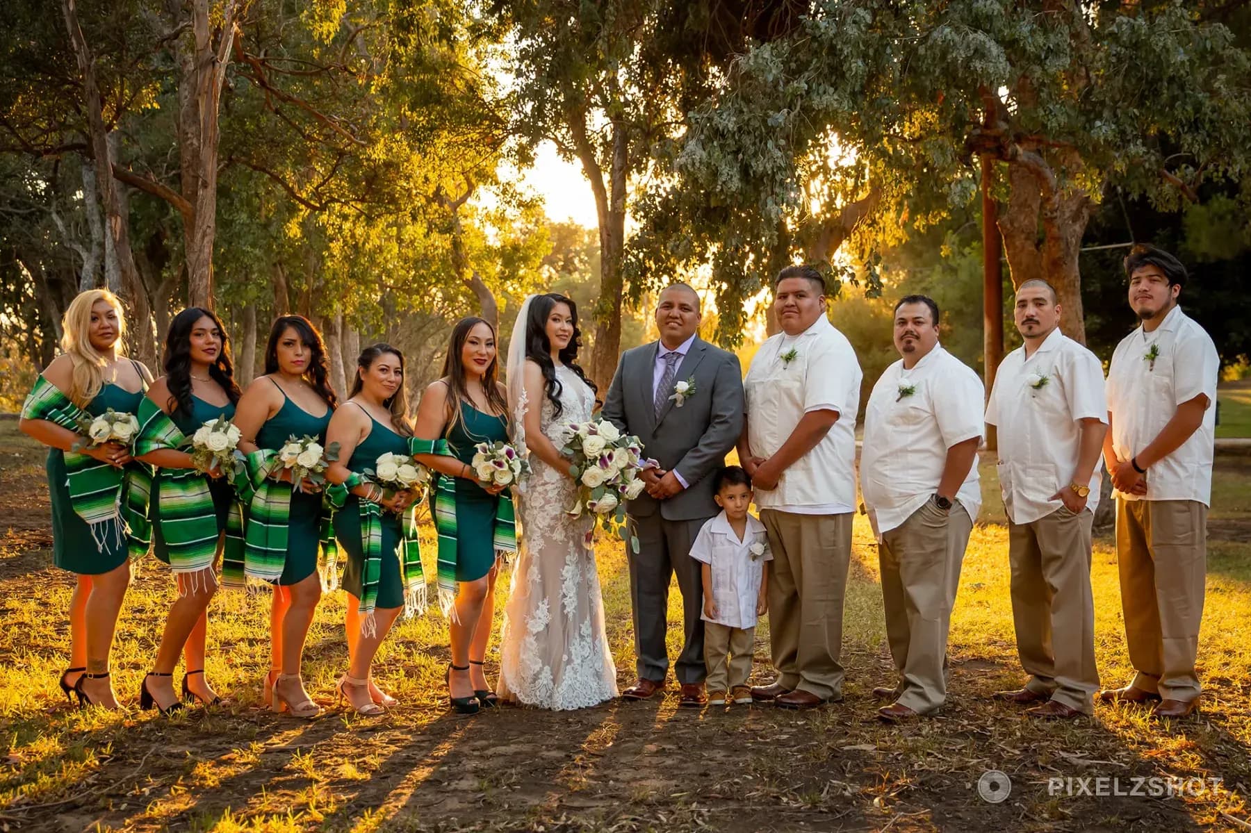 Natalie and Eduardo with their wedding party in emerald dresses and guayaberas at sunset