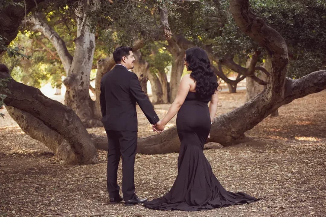 Engaged couple walking hand in hand beneath a canopy of oak trees