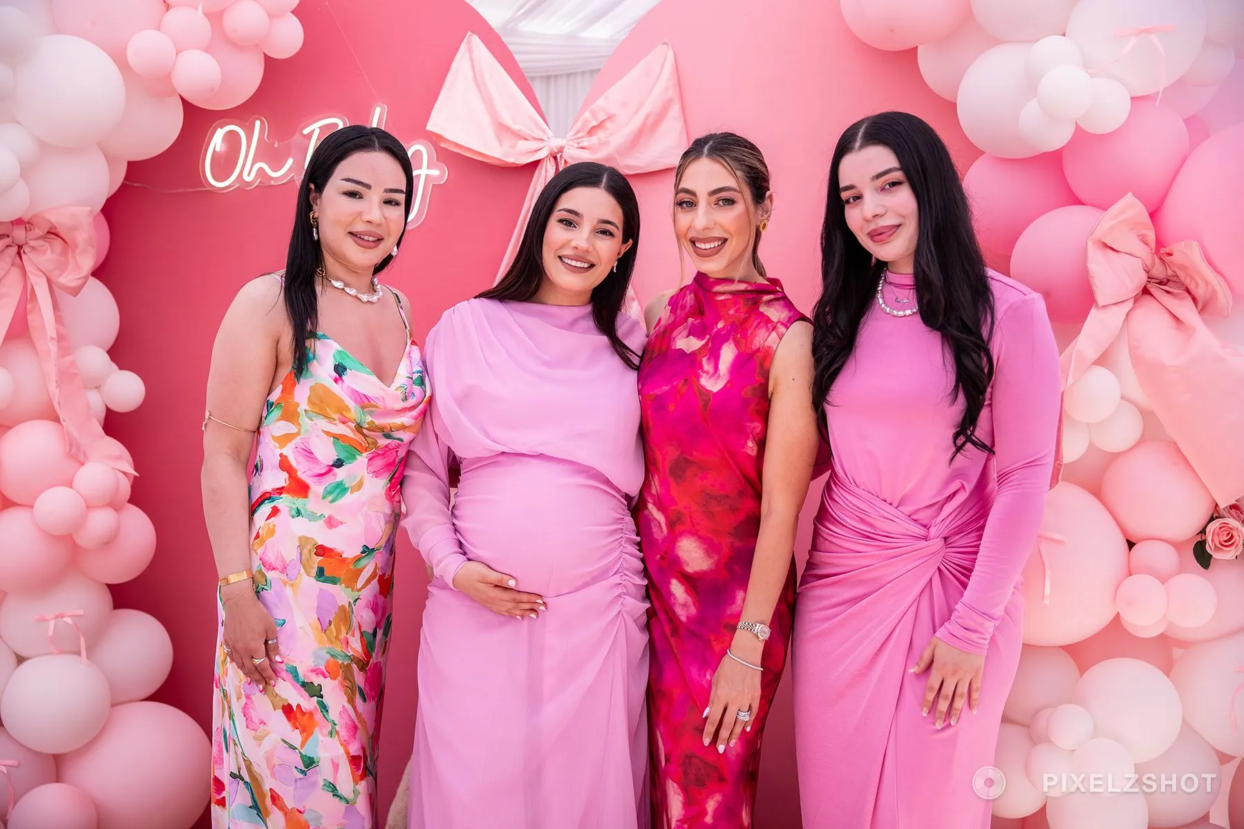 Four guests lined up in pink against the balloon arch, the guest of honour second from the left