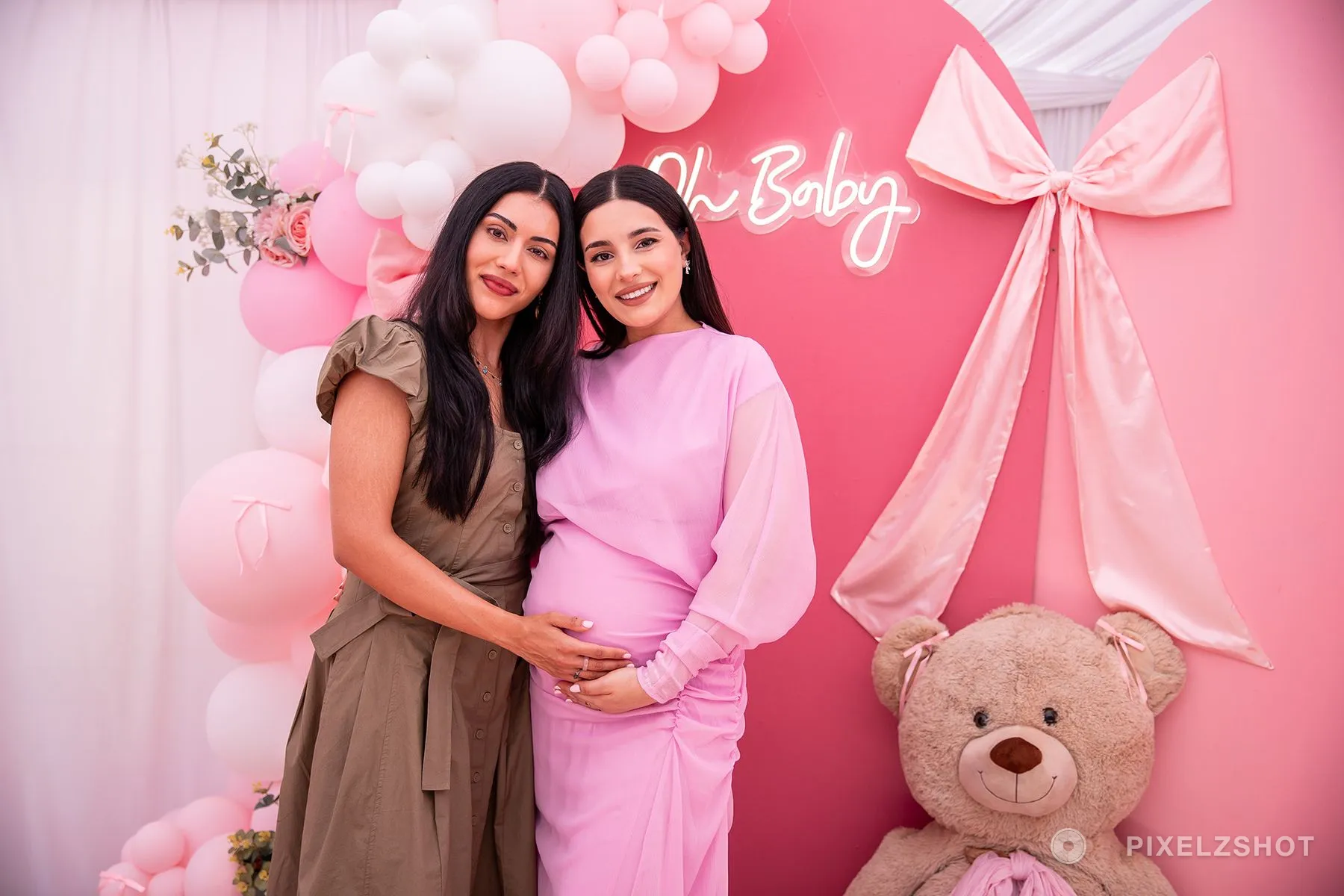 Two of them standing cheek to cheek at the backdrop, one with a hand resting on the bump