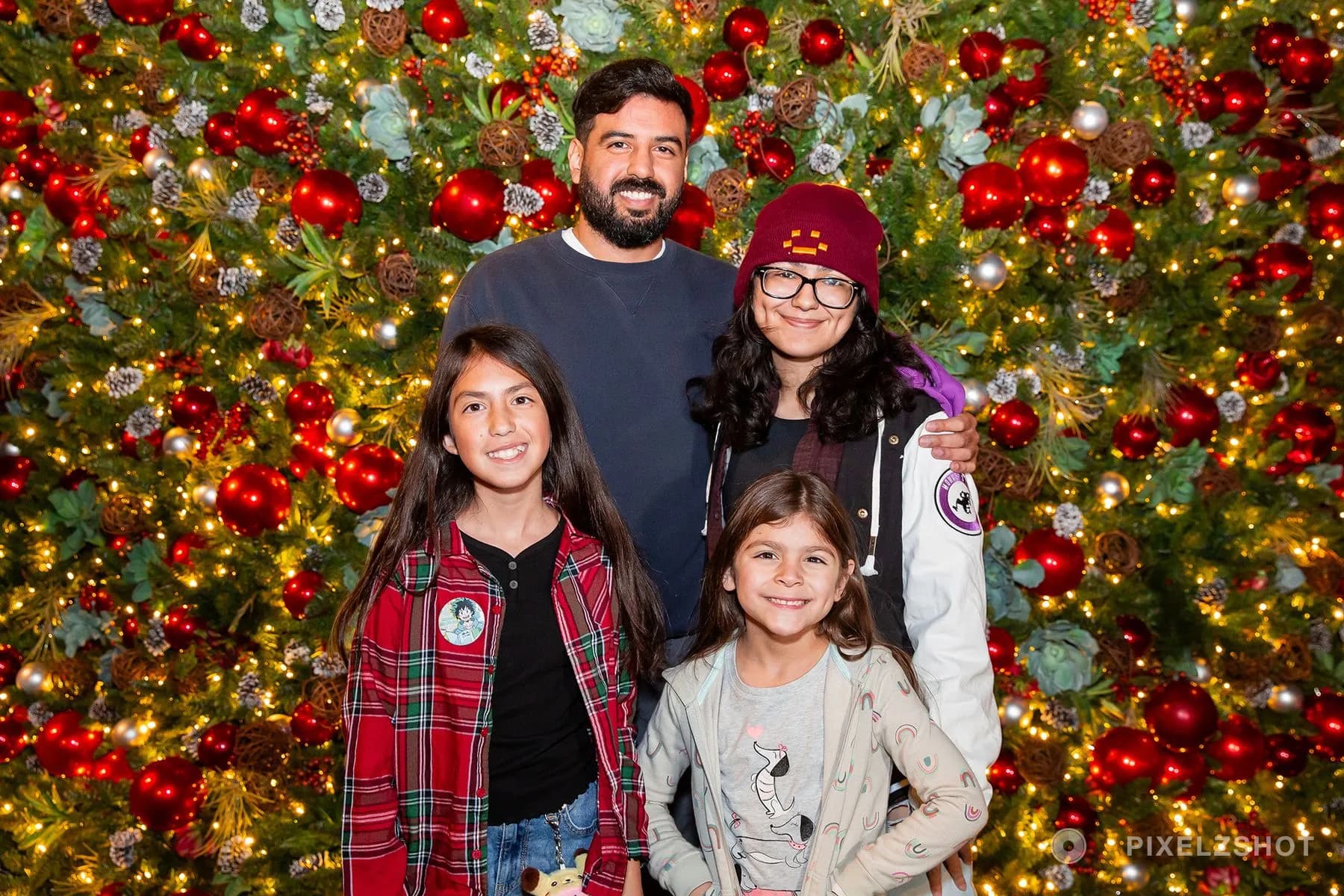 A family of four posed together against the tree, the two youngest in front and the older two behind