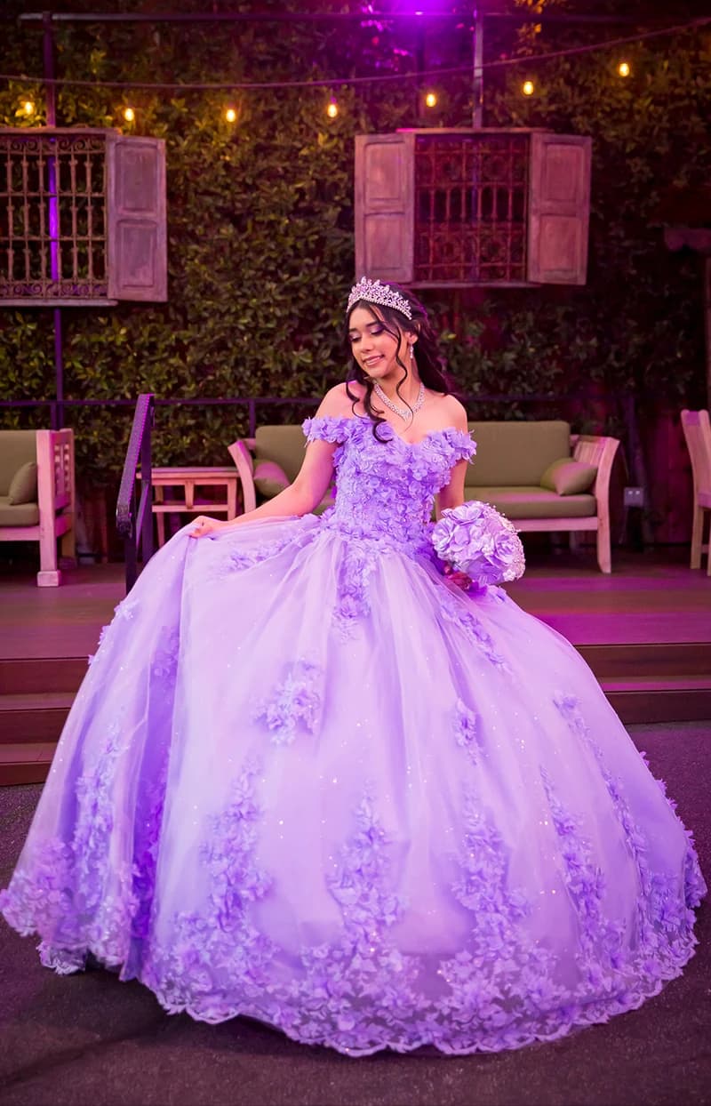 Quinceañera in a lavender ball gown holding a bouquet on a string-lit patio